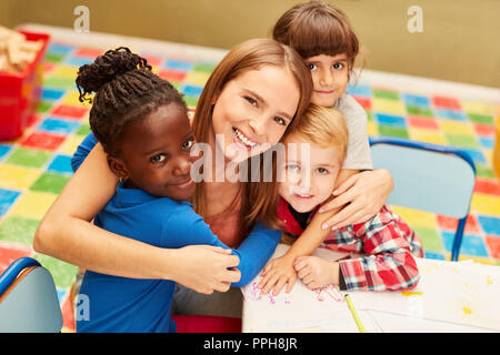 Happy woman as a teacher or childminder together with children in the day care center Stock Photo