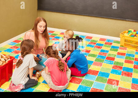 Teacher or childminder reading from a children's book in kindergarten Stock Photo