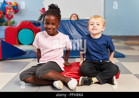 Two kids playing kid sports in multicultural kindergarten in the gym Stock Photo