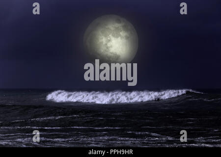 Big white Sea wave approaching the portuguese coast in a misty and dark full moon night Stock Photo