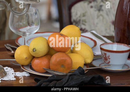 Plate with natural looking fruit, oranges and lemons on a table Stock Photo