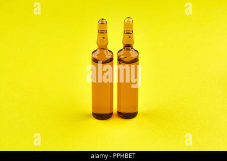 Brown ampoules with medicine on yellow background. Stock Photo