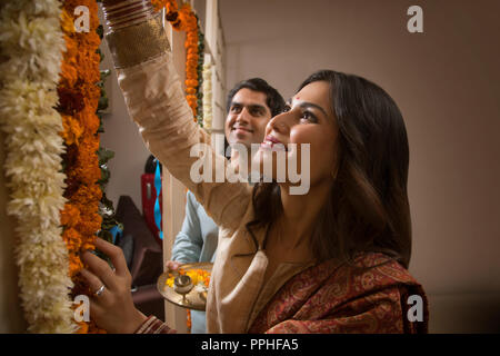 Close up of happy young couple in traditional dress decorating their home with flowers. Stock Photo