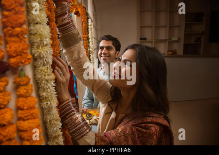 Close up of happy young couple in traditional dress decorating their home with flowers. Stock Photo