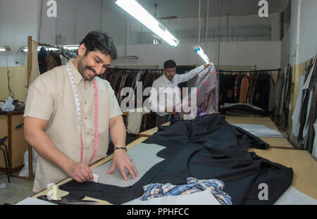 Smiling tailor making markings on cloth in his workshop. Stock Photo