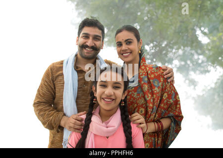 Portrait of a smiling village man standing with his wife and daughter posing for a family photo. Stock Photo