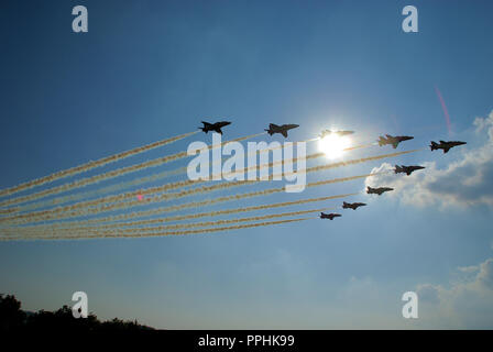 Red Arrows. RAF, Royal Air Force aerobatic display team flying in front of the sun. Formation flypast. Sunburst. Blue sky Stock Photo