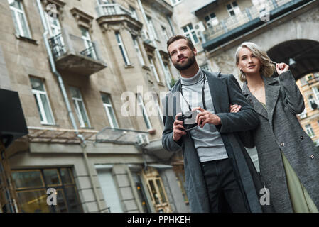 Romantic date outdoors. Young couple walking on the city street taking photos on camera smiling excited Stock Photo