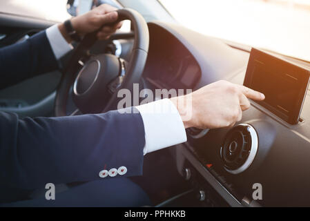 Close-up of a man hand touching black screen smartphone on a dashboard. Stock Photo