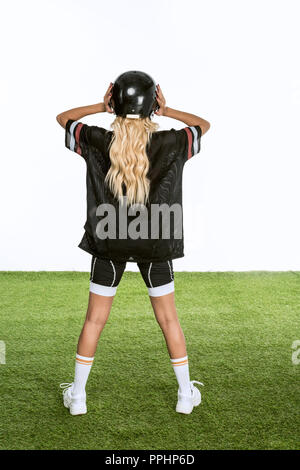 rear view of woman in american football uniform standing on grass isolated on white Stock Photo