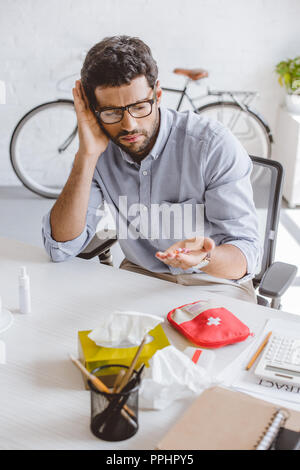 scared sick manager holding pills in hand in office Stock Photo