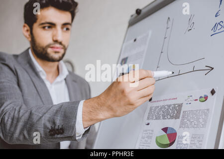 handsome businessman drawing chart on flipchart in office Stock Photo