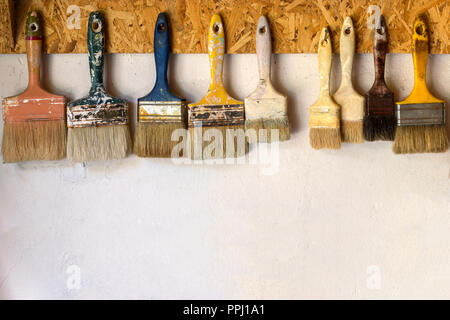 Old paint brushes hanging on a wall Stock Photo