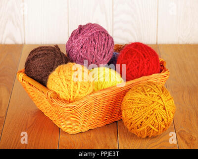 colorful yarn balls in wicker basket on wooden background Stock Photo
