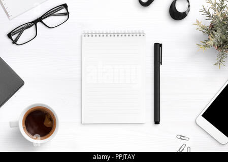 Empty writing pad on office desk surrounder with office supplies. Top view composition. Stock Photo