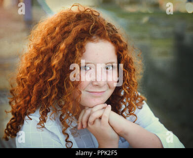 Pretty redhead young girl with curly hair portrait outdoors Stock Photo