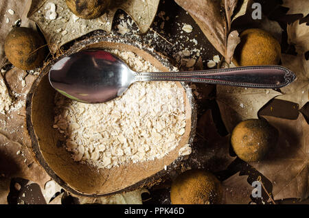 Oatmeal dish served in the middle of a dry coconut, garnished with dried and yellowish lemons, dried leaves on a brown background. Stock Photo