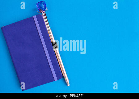 Purple notebook with pen on a blue background Stock Photo