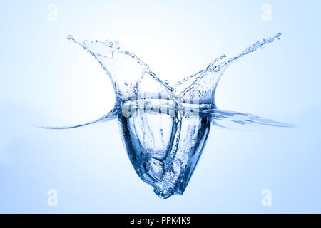 Single icecube splashing into water with abstract water fountain on light blue background Stock Photo