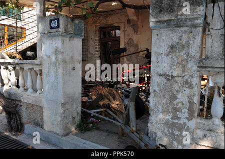 Abandoned building in Petrovac, Montenegro. Front yard covered with junk. Stock Photo