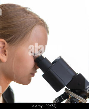 A 9 year old girl looks into an eyepiece of a microscope. Isolated against white background Stock Photo