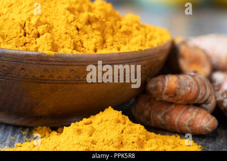 Turmeric powder in a wooden bowl and on the table with turmeric roots. Stock Photo