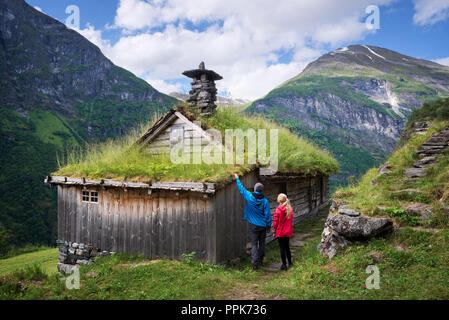 Kagefla - mountain farms on the mountainsides along the Geirangerfjorden fjord. Tourist attraction of Norway. A pair of travelers visiting traditional Stock Photo
