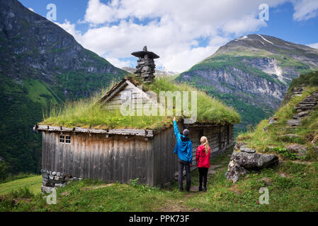 Kagefla - mountain farms with turf houses along the Geirangerfjorden fjord. Tourist attraction near Geiranger city, Norway. Travelers visiting traditi Stock Photo
