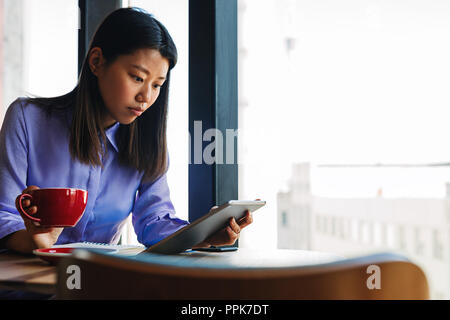 Woman sitting in cafe and using tablet pc Stock Photo
