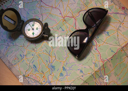 Sunglasses on a road map next to a compass to guide you better in travel Stock Photo