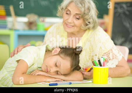 Portrait of grandmother awakening granddaughter who sleeping at table Stock Photo