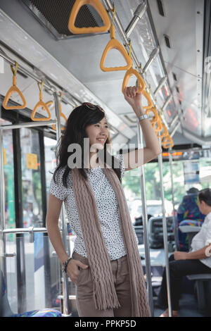 Beautiful young woman standing in bus Stock Photo