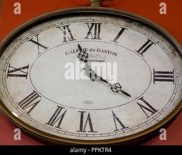 1885 Galerie du Gaston Oval Wall Clock on a red wall, marking