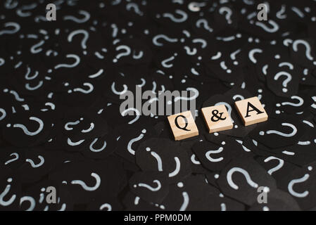 wooden alphabet tiles with Q&A letter on black paper with QUESTION MARK. Concept of Question and Answer Q&A online assist Stock Photo