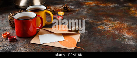 Two colored enamel cups of tea, two envelops, watercolors in cuvettes, , autumn leaves and bumps on a rusty brown background Stock Photo