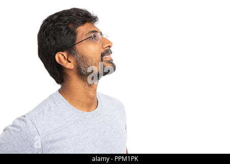 Indian man with eyeglasses or spectacles looking up and smiling with copyspace for advertising isolated on white background Stock Photo