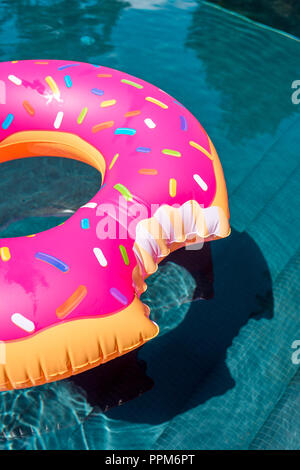 close-up shot of inflatable ring in shape of bitten donut floating in swimming pool Stock Photo