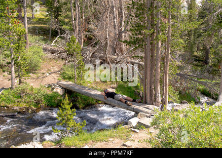 A backpacker takes a break along the John Muir Trail, Duck Creek Bridge, John Muir Wilderness, Sierra National Forest, Sierra Nevada Mountains, Califo Stock Photo