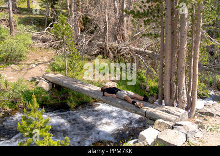 A backpacker takes a break along the John Muir Trail, Duck Creek Bridge, John Muir Wilderness, Sierra National Forest, Sierra Nevada Mountains, Califo Stock Photo