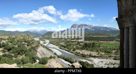 A view from Holy Mary Church tower, Ainsa, Spanish Pyrenees, with rocky mountains, trees, a little stream running through the valley, and a blue sky. Stock Photo