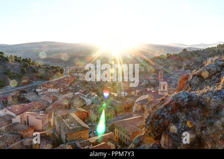 A landscape with the shining sun setting at dusk behind the mountains around the Spanish Aragonese small town of Daroca Stock Photo