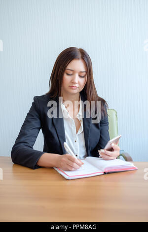 Busy female office worker going to make notes. Stock Photo