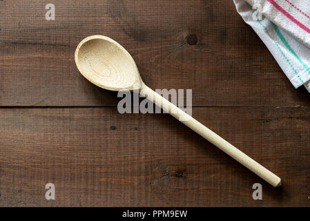 Wooden spoon lying on a cloth napkin. On a dark wood background. Stock Photo