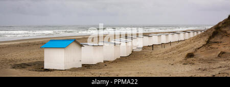 View on the beach huts on the west coast area of Texel. Panoramic view on the North Sea on a day in autumn with beautiful waves and a heavy grey sky. Stock Photo