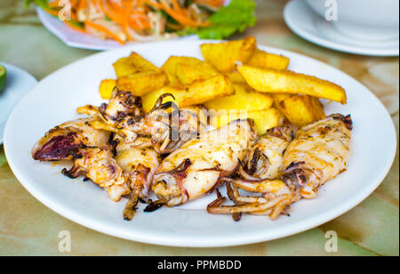 Grilled squid with french fries on a plate. Seafood meal Stock Photo