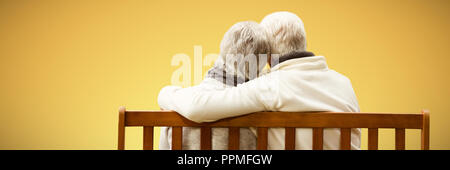 Composite image of  senior couple embracing on a bench Stock Photo
