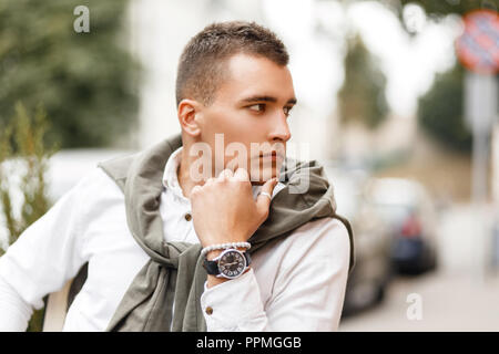 Successful young man businessman in a stylish white shirt with a sweater sits in a cafe in the city Stock Photo