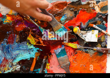 set of an artist's tool on a background with oil paint. Man's hand draws with a brush Stock Photo