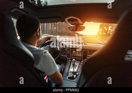 Man in a premium car with an interior is driving at sunset. Concept travel by car Stock Photo