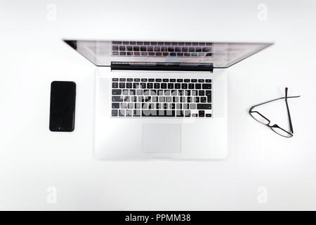 Creative workplace with laptop, smartphone and glasses on a white table Stock Photo